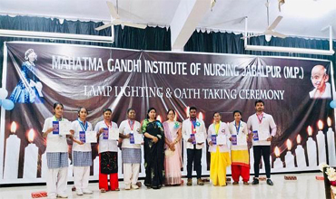 A picture of students standing showing their achievents during the lighting and oath taking ceremony conducted in Mahatma Gandhi Institute of Nursing.